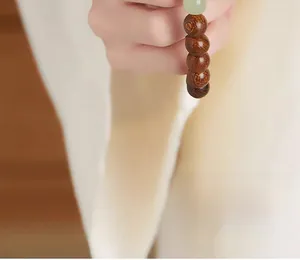 Macro shot of dark brown wooden prayer beads with a smooth green jade accent stone