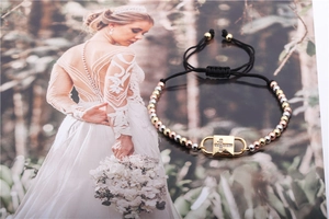 Detail of adjustable black cord bracelet with tri-color copper beads and zircon cross charm