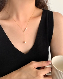 Elegant gold S925 silver necklace with four vertical pearls shown on a black V-neck top