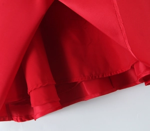 Detailed macro view of the red satin dress hem showing premium stitching and fabric texture