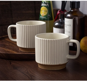 Detail of cream ceramic mugs with vertical ribs and brown base on wooden tray