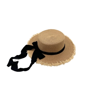 Detail of boater straw hat with black ribbon tie and decorative frayed edge brim