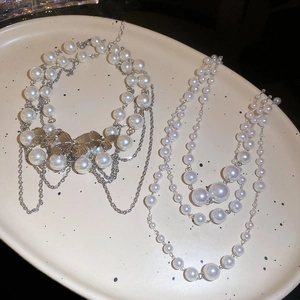 Detail of layered pearl necklaces with silver butterfly charms on a ceramic tray