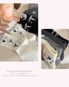 Gros plan sur la broderie mouton et le texte des chaussettes en coton noir, blanc et gris