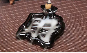 Detail of creative black ceramic incense burner shaped like Chinese character Cai on bamboo mat
