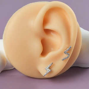 Close-up of lightning and S-curve silver earrings with sparkling white cubic zirconia