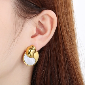 Elegant gold-tone circular shell earrings with white mother-of-pearl inlay worn by model