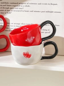 Detail of red and white ceramic heart mugs with Love lettering and black handles