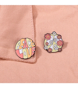 Detailed close-up of Peace Love enamel pins with floral patterns on orange denim fabric