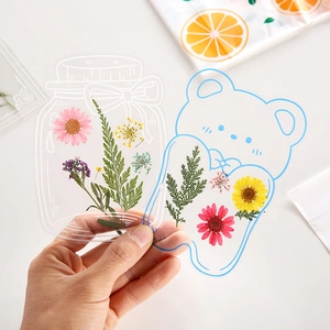 Handgehaltenes transparentes PET-Lesezeichen mit bunten Trockenblumen in Flaschenform