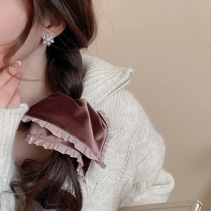 Close-up of brown velvet scrunchie with pink lace ruffle trim on model's braided hair