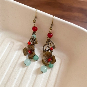 Gros plan de boucles d'oreilles ethniques en bronze avec perles rouges et vertes sur bois