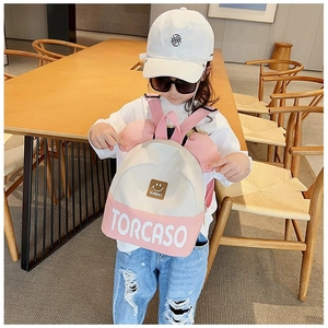 Close-up of pink and beige kids backpack featuring cute ear decor and Sunday smiley badge