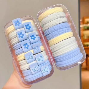 Detail of high-elastic macaron scrunchies in transparent boxes with cute flower accents