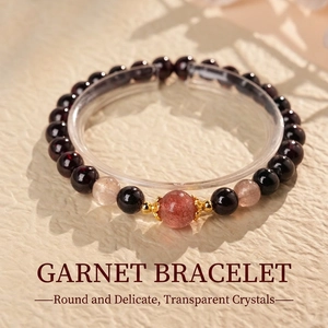 Deep red garnet bead bracelet with translucent stones and gold floral accents on white