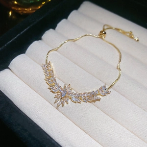 Détail du bracelet doré ajustable avec feuilles de zircon sur boîte en velours blanc