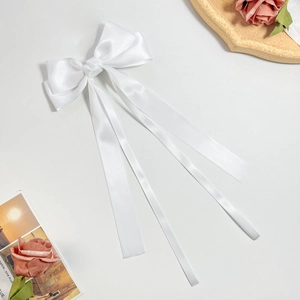 Close-up of elegant white satin ribbon hair clip with long streamers on white background