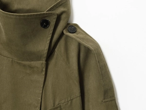 Détail du trench-coat vert olive avec texture en toile et boutons noirs élégants