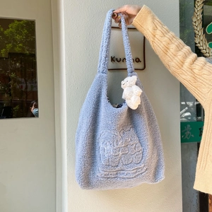 Close-up of light blue plush tote with teddy bear embroidery and a cute bear charm