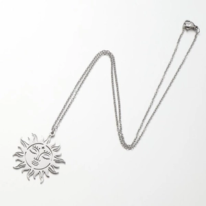 Close-up of silver-toned sun face pendant necklace with detailed hollow-out engravings