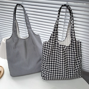 Detail of classic black and white polka dot and striped canvas tote bags on a table