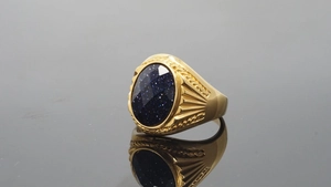 Macro detail of gold-plated ring showing oval blue sandstone inlay and grooved side patterns