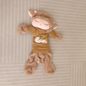 Detail of a brown curly plush lamb toy wearing a yellow LOVE sweater on a rug