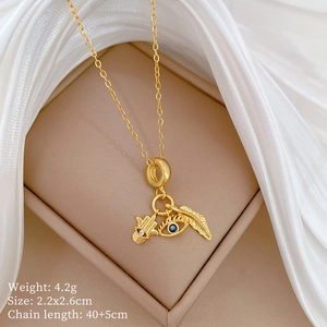 Macro shot of gold necklace with evil eye and leaf pendants on white silk fabric