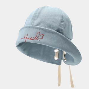 Detailaufnahme des hellblauen Denim-Anglerhuts mit roter Stickerei und Tunnelzugband