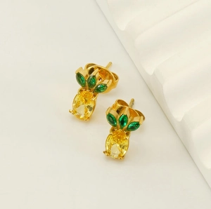 Macro view of pineapple-shaped earrings with yellow zircon and green marquise stones