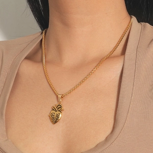 Dettaglio di una collana con ciondolo a cuore anatomico dorato e catena a corda intrecciata