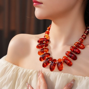 Close-up of irregular amber beads necklace on model with vintage brown and gold accents