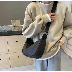 Minimalist black nylon dumpling bag crossbody style on model in a modern interior
