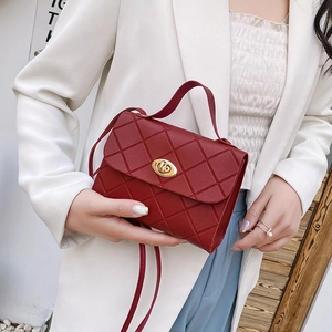 Elegant red quilted crossbody bag with golden twist lock worn by a model in white blazer