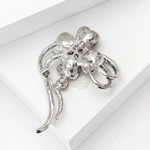 Detailed back view of a silver four-leaf clover brooch showing pin structure and texture