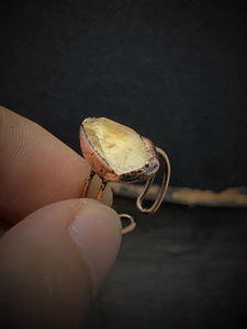 Macro detail of handmade bronze ring featuring a raw yellow gemstone and adjustable band