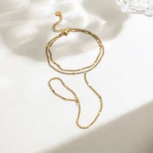 Detailed shot of double-layered gold chain bracelet with sequin charms on white background