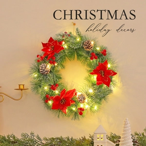 Illuminated Christmas wreath with red flowers, pine cones and warm LED lights for door decor