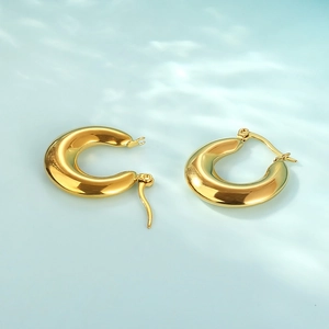 Detailed macro view of polished gold oval hoop earrings with water ripple lighting effects