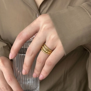 Detail view of a triple-layered twisted gold rope ring worn on finger with minimalist style