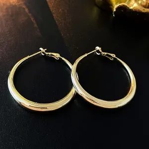 Elegant gold chunky hoop earrings with polished metallic finish on a textured background