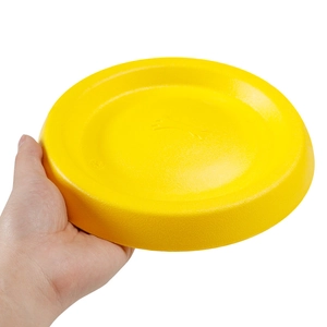 Detail view of durable bright yellow pet flying disc held by hand for size reference
