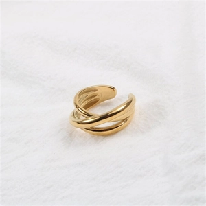 Detailed view of multilayer gold stainless steel ring on white textured fabric background