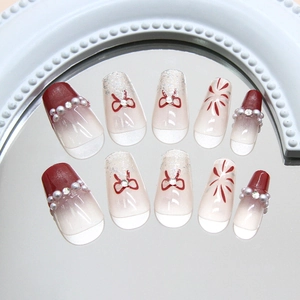 Faux ongles rouges à paillettes avec perles et nœuds papillons, design effet œil de chat