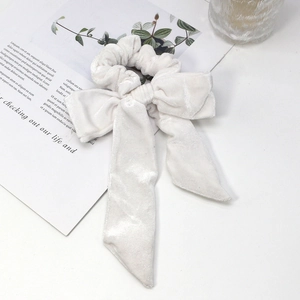 Detailed view of a creamy white velvet scrunchie with a large bow and long streamers