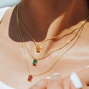 Detailed view of triple-layered gold necklaces with colorful zircon gemstone pendants