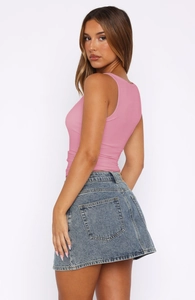 Detail view of pink ribbed sleeveless crop top showing texture on model with studio light