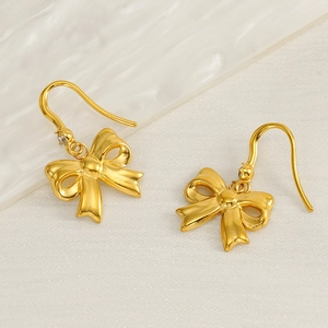 Elegant gold-plated bow earrings with crystal studs on a white silk background