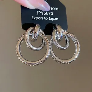 Boucles d'oreilles pendantes double cercles argentés avec finitions lisses et texturées
