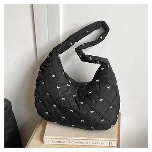 Detail der schwarzen Stepptasche mit weißen Schleifen-Stickereien und glattem Reißverschluss